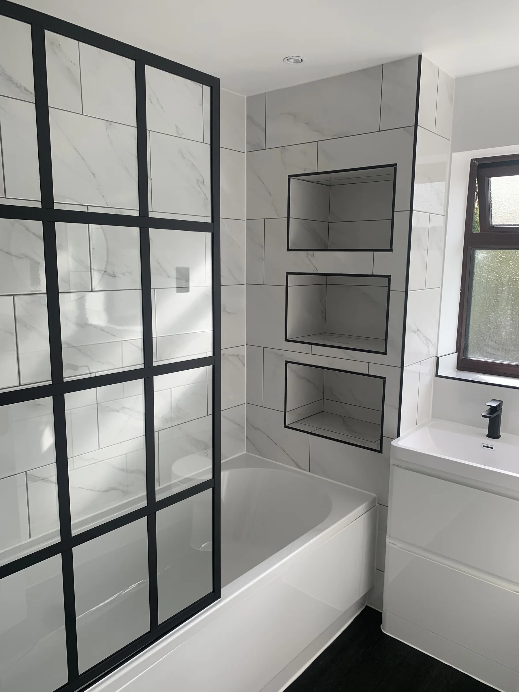 Modern marble-effect bathroom with black-framed bath screen