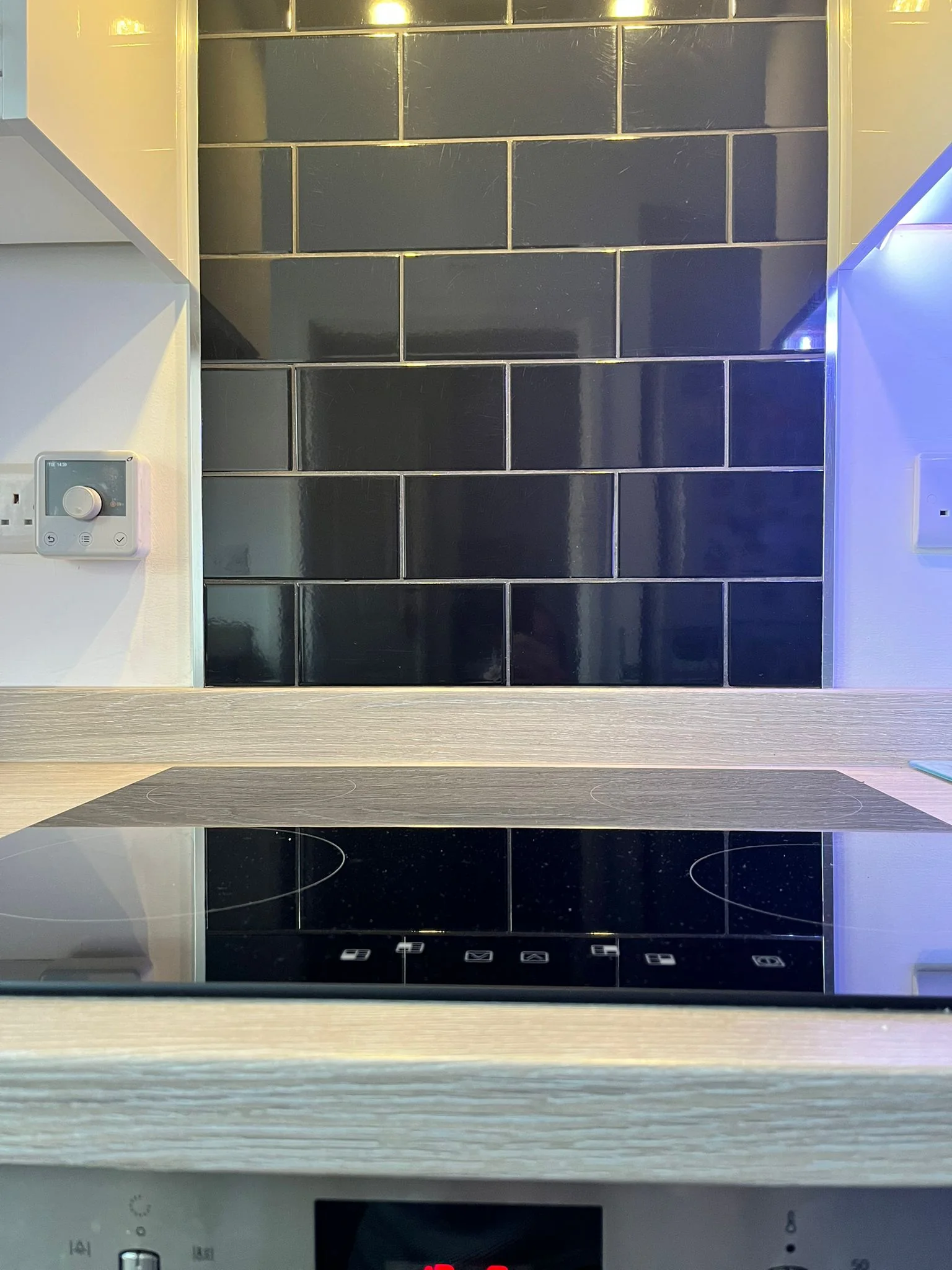 Gloss black tiled kitchen splashback